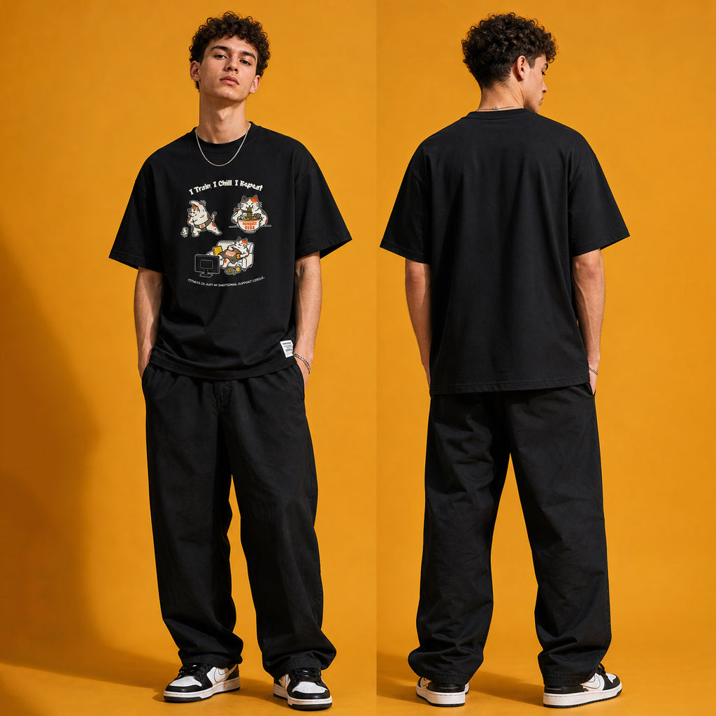 Model wearing the I Train I Chill I Repeat heavyweight loose fit graphic tee in Vintage Black, shown in styled product photography.