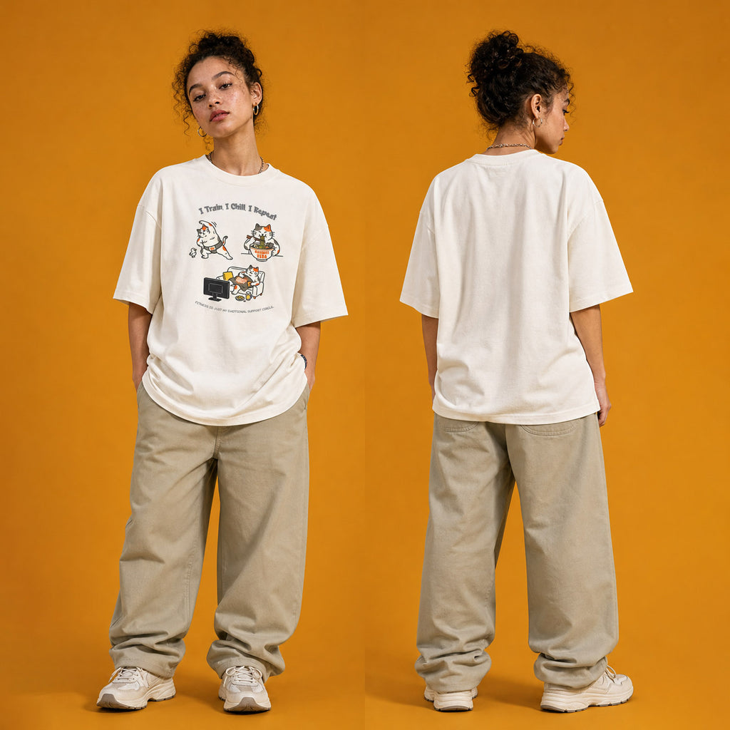 Model wearing the I Train I Chill I Repeat heavyweight loose fit graphic tee in Off White, shown in styled product photography.